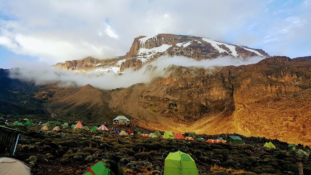 Tents at a high camp below the snow-streaked summit of Kilimanjaro